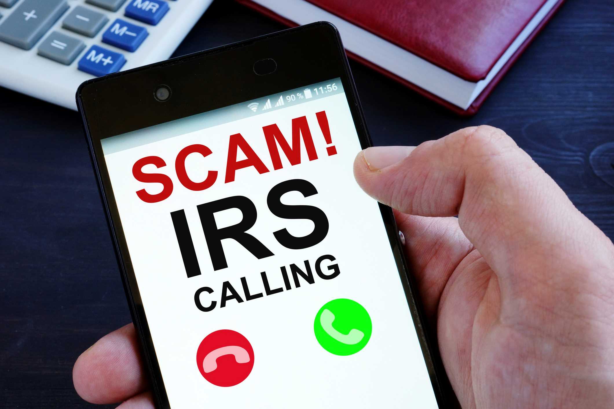 Mobile phone screen reads SCAM! IRS Calling