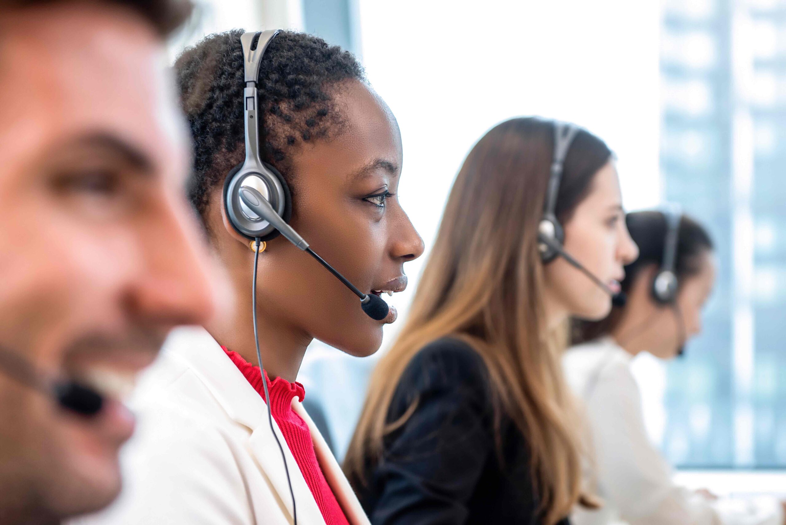 Call center agents wearing headsets and looking a computer screens.