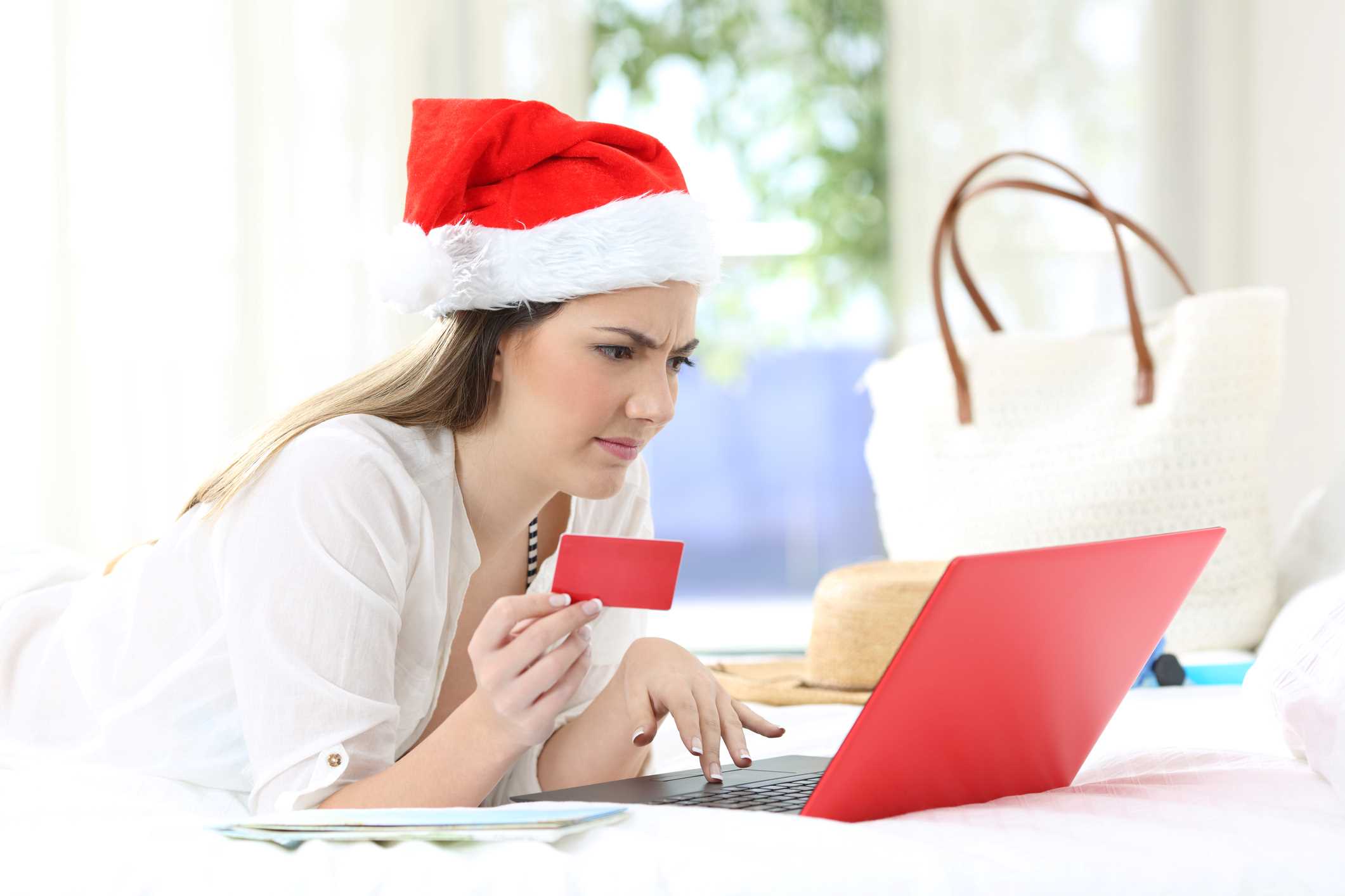 A woman wearing a Santa hat shopping online.