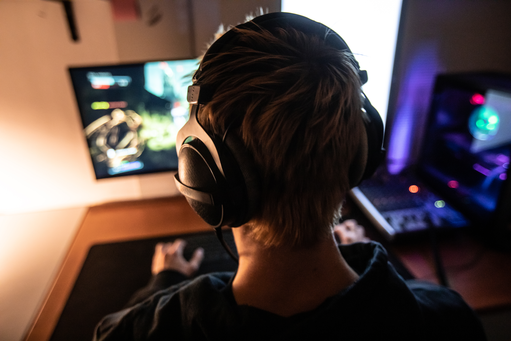 A young man is playing video games while wearing a headset.