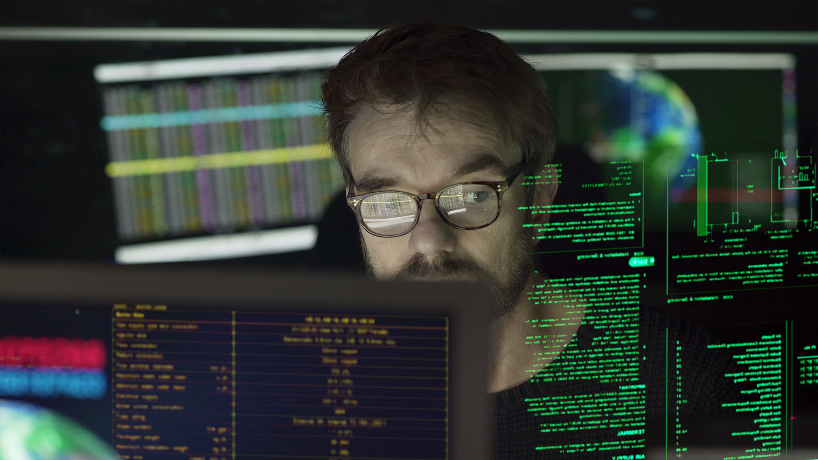 Man looking a various computer screens full of code.
