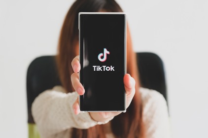 Woman showing her smartphone screen with the TikTok app displaying.