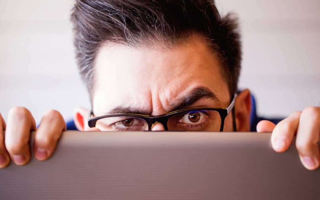 Man peeking up from top of laptop screen