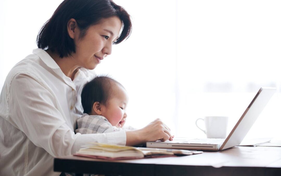 Mother with baby on her lap researching credit freezes on a laptop