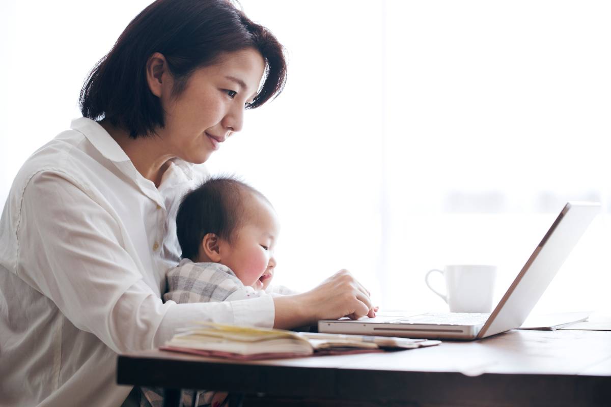Mother with baby on her lap researching credit freezes on a laptop