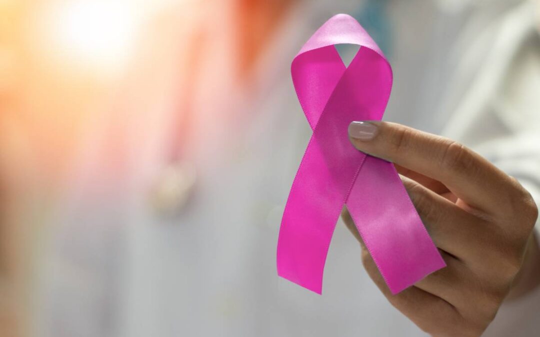 Pink Breast Cancer Awareness ribbon being held by a woman.