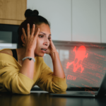 Woman distressed because she is getting a Hacked message on her desktop computer.